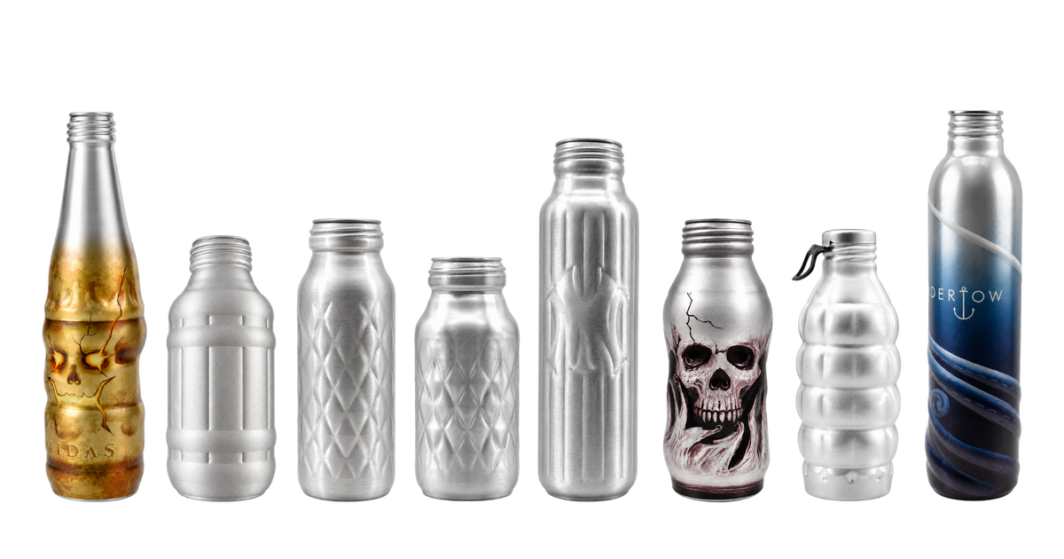 A lineup of eight custom die-cast aluminum and glass beverage bottles with various designs, including embossed patterns, a skull graphic, and a blue gradient design, set against a plain white background.